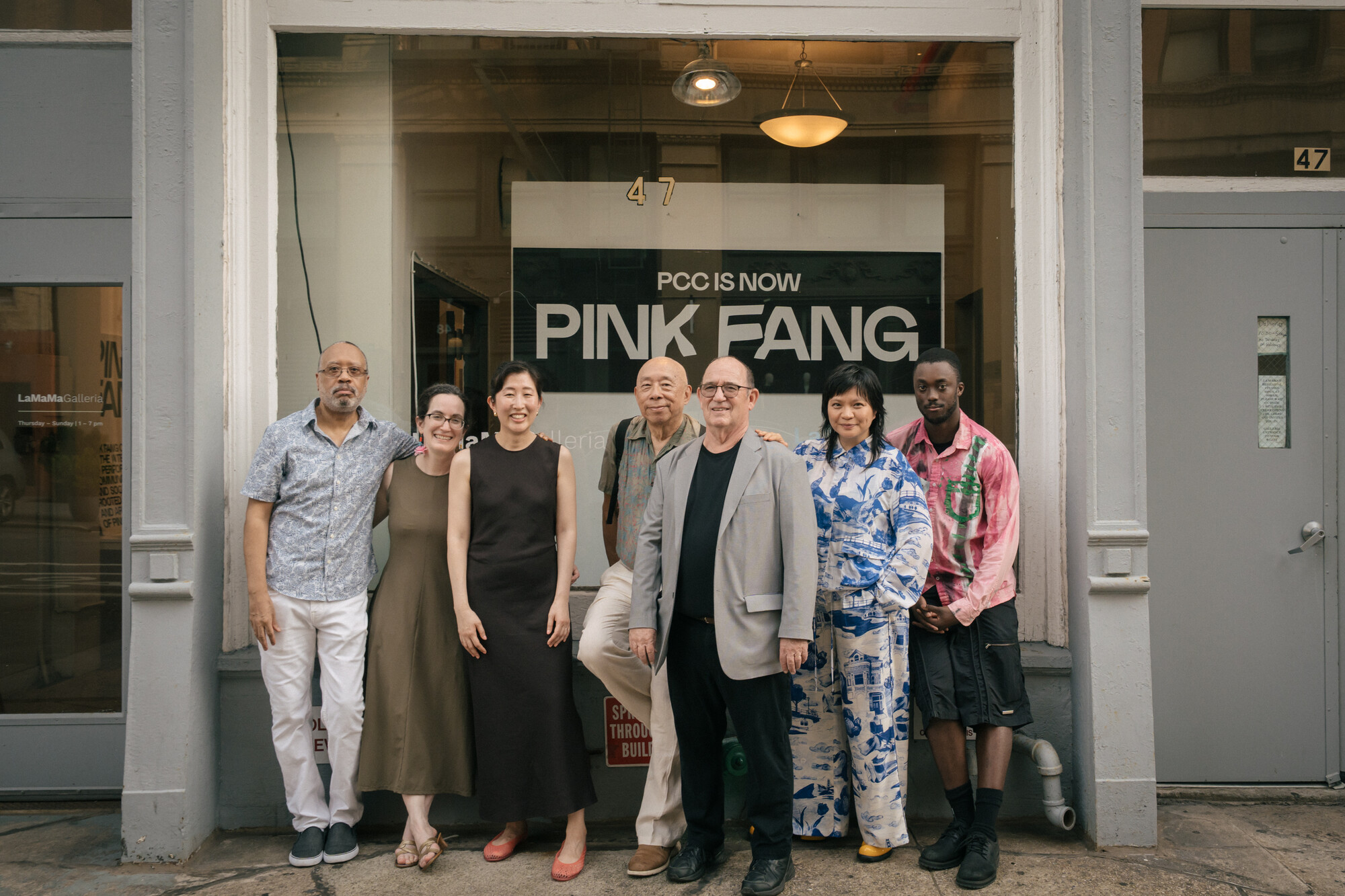 A group of people standing in front of a Pink Fang sign.