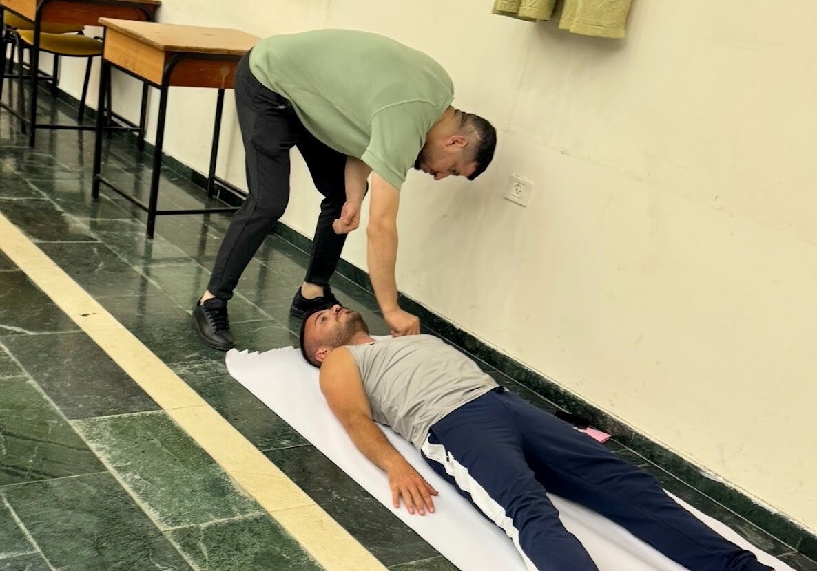 A performer traces another's body lying down.