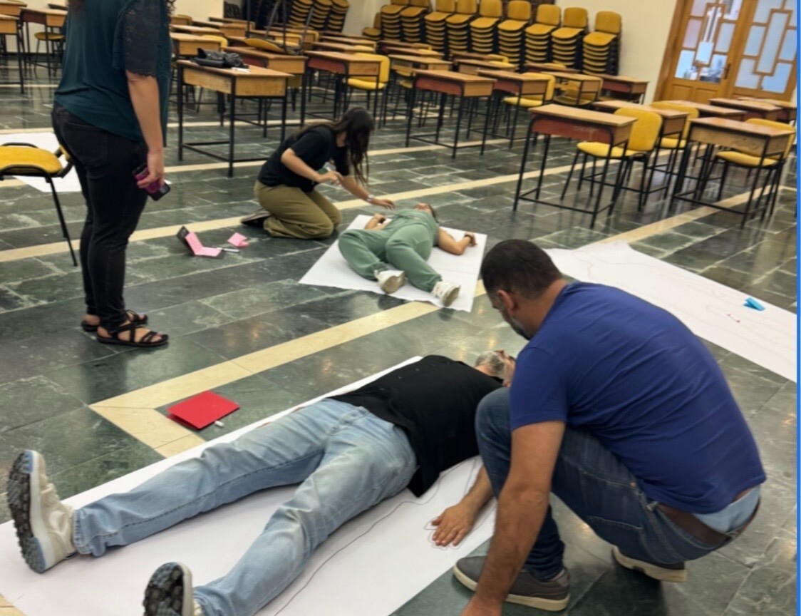 Two participants lie on the ground to be traced.