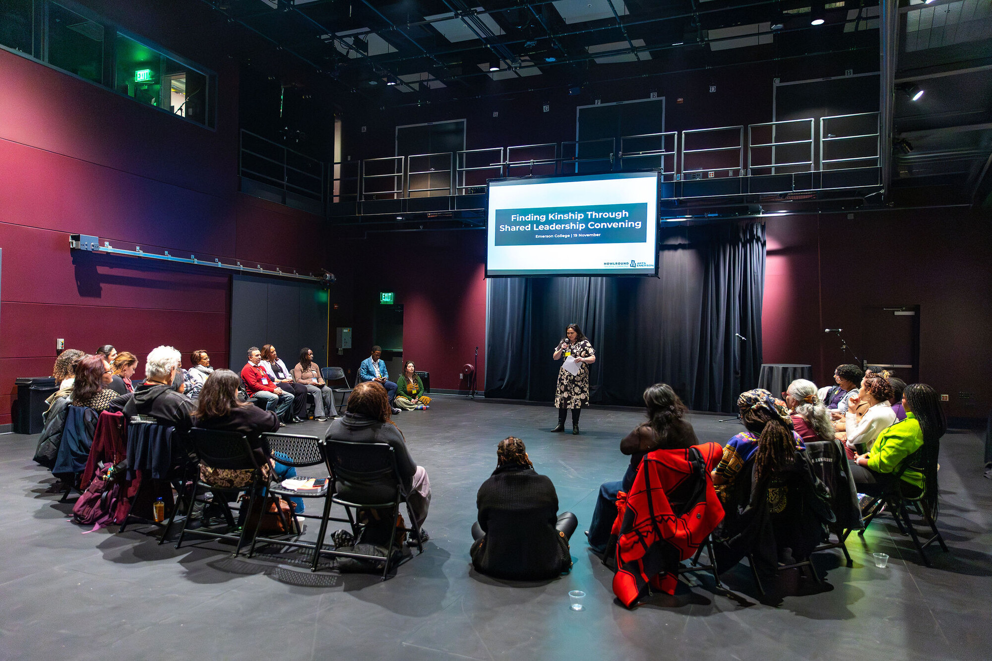 A person addresses a seated circle of people.