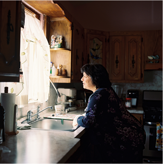 A woman looks out a kitchen window.