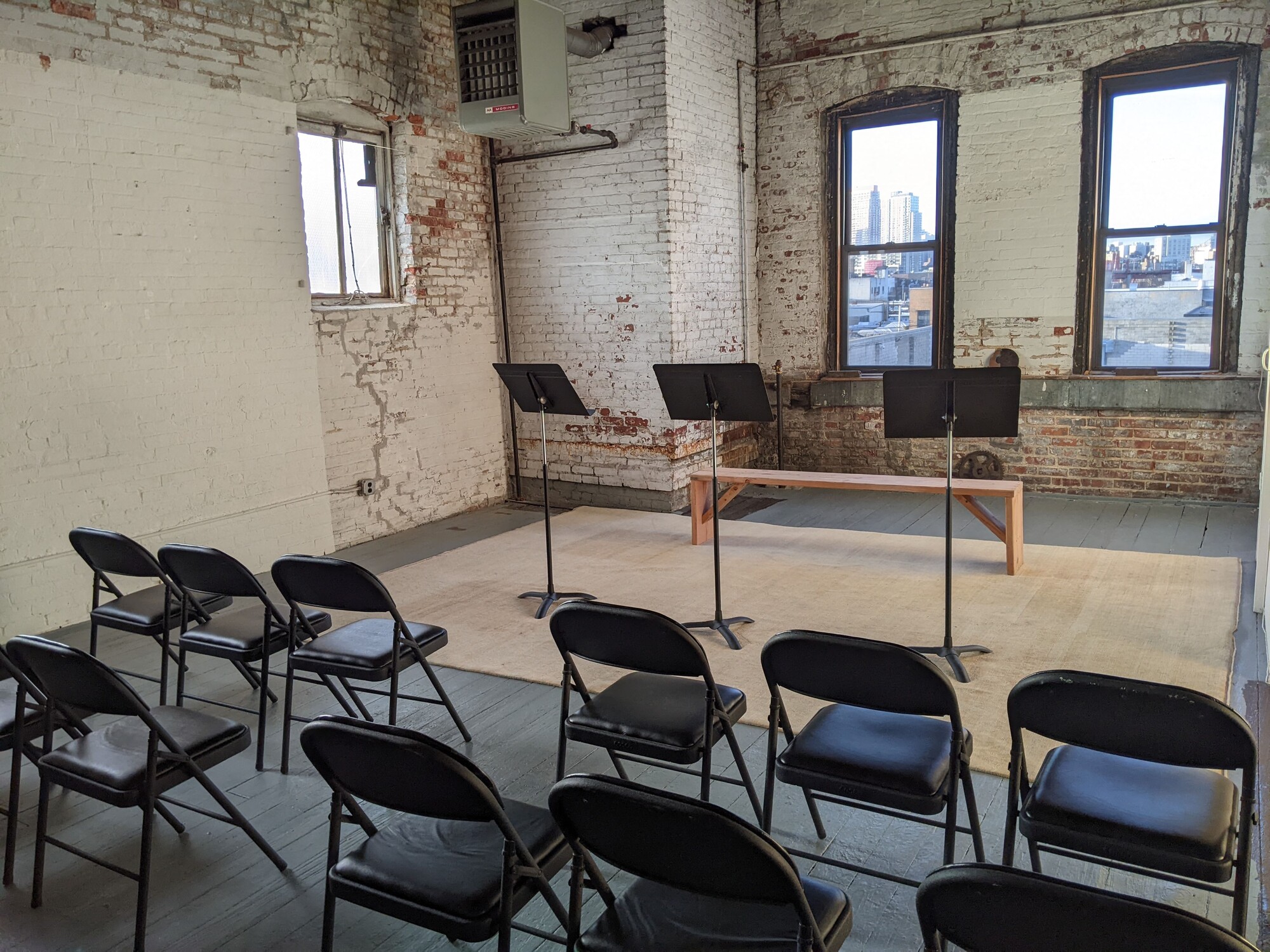 A series of chairs sit un front of three music stands.