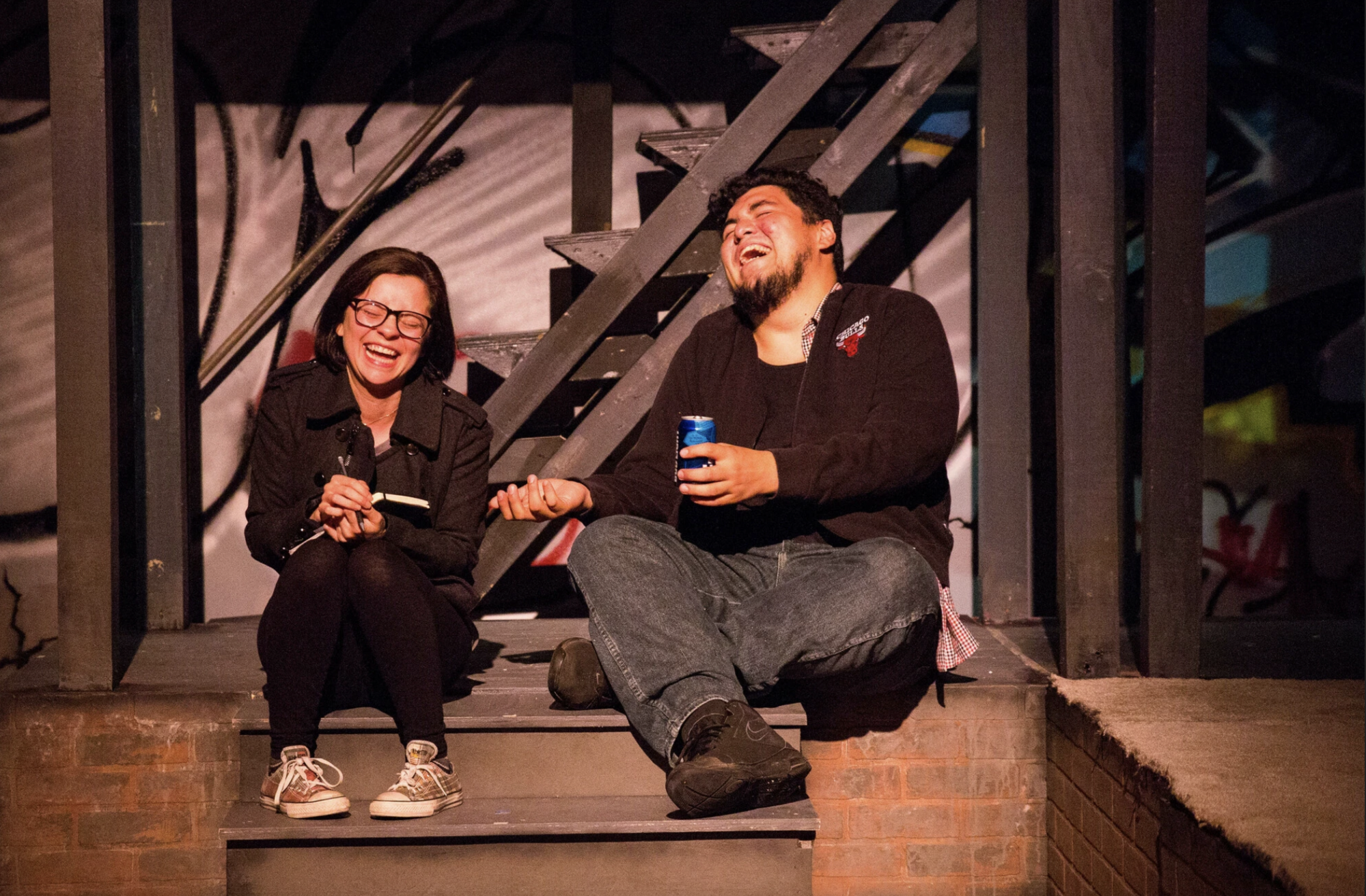 Two people laugh onstage together