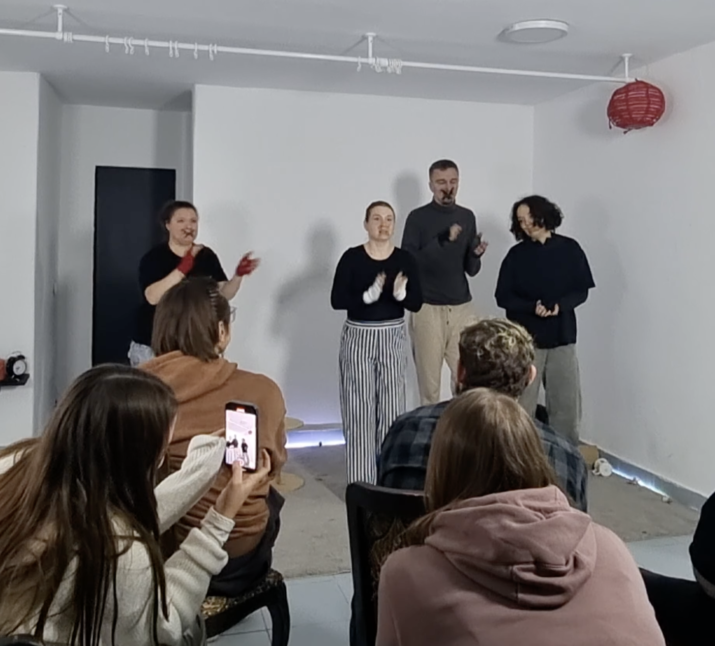 A group of people clap in a small room.