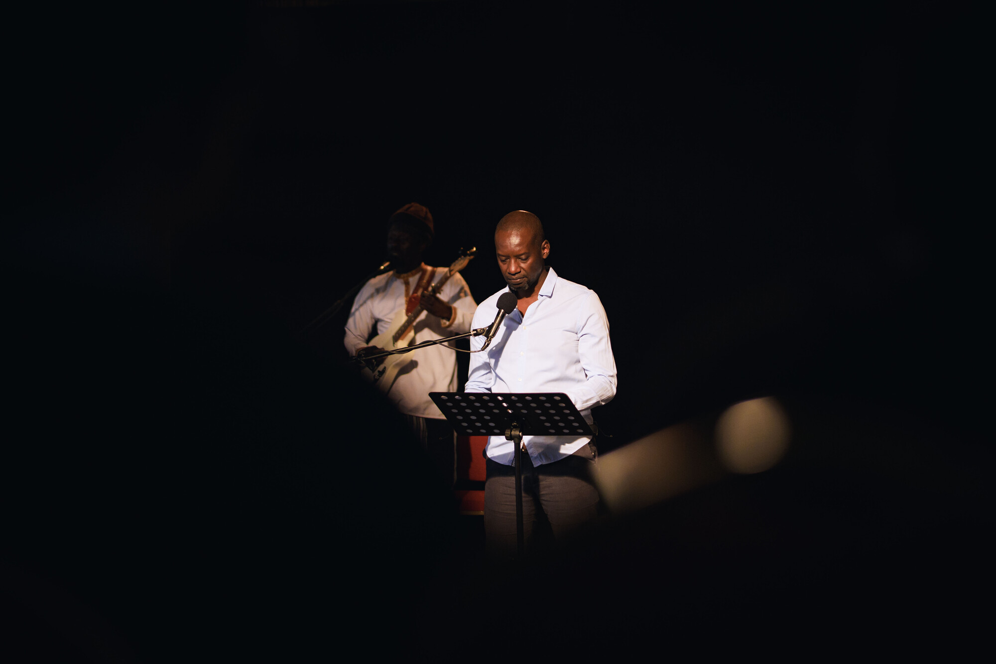 A person in a spotlight speaks into a microphone.