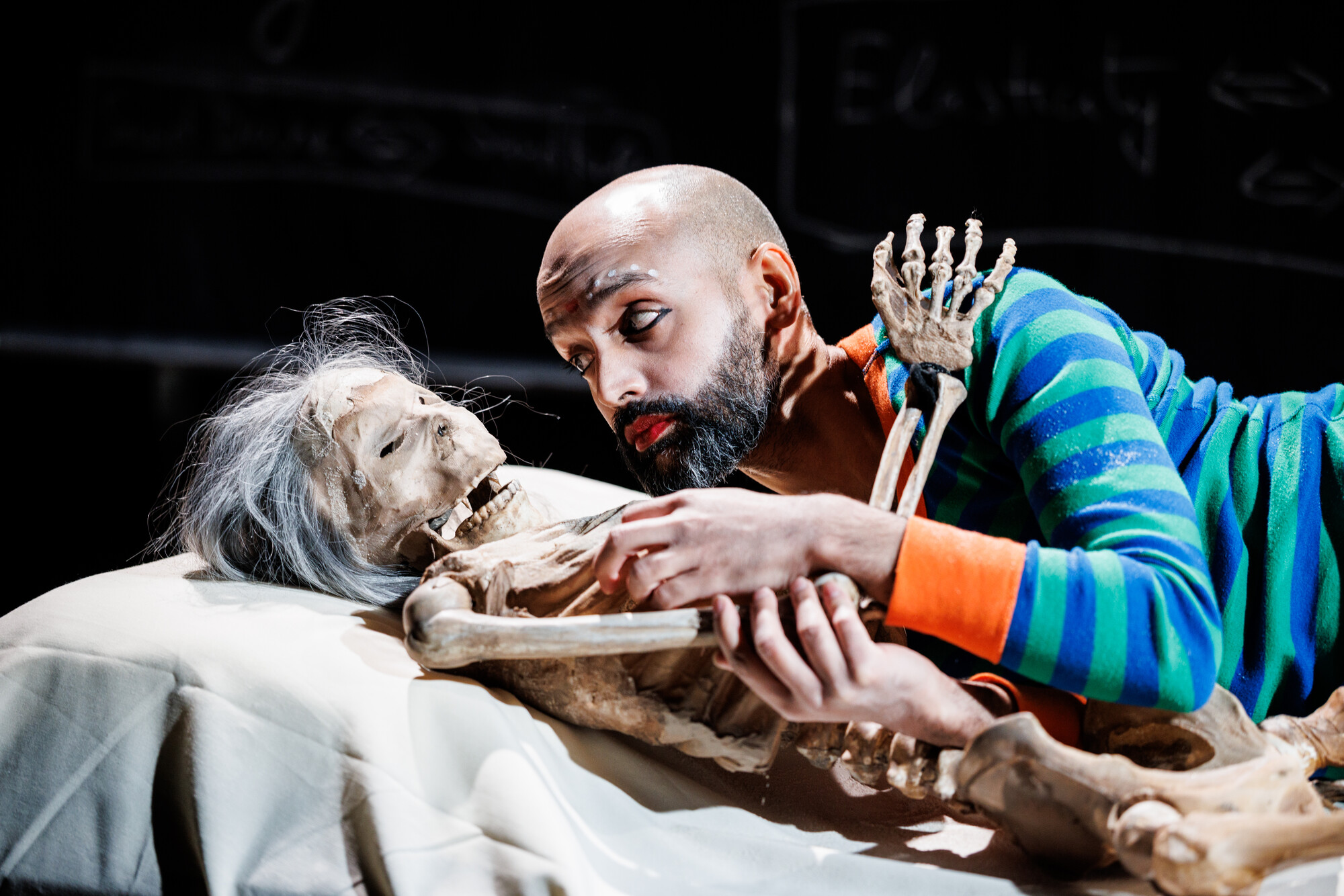 a person cuddles up to a skeleton in bed.