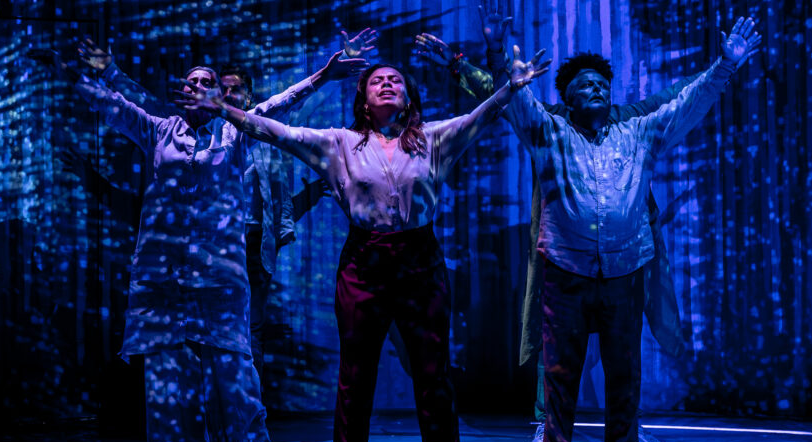 Three people stand onstage with raised hands.