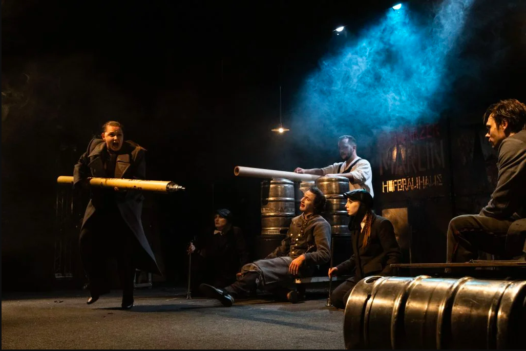 A person charges forward with a weapon in a stage performance.