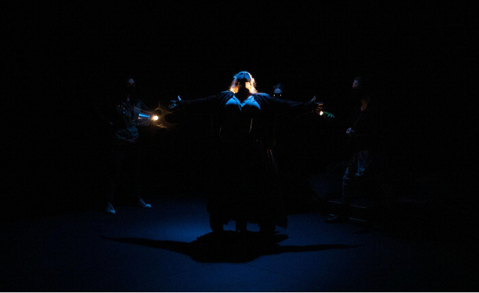 A dimly lit stage of actors.