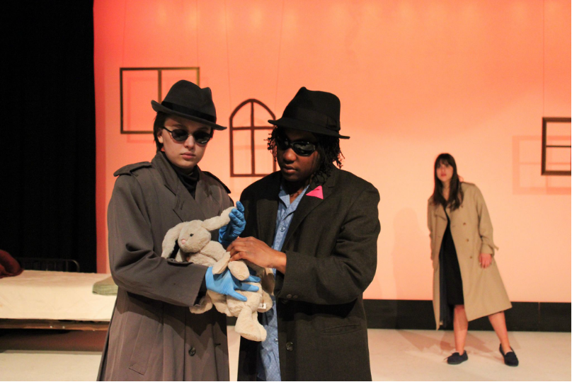 Two people wear fedoras onstage.