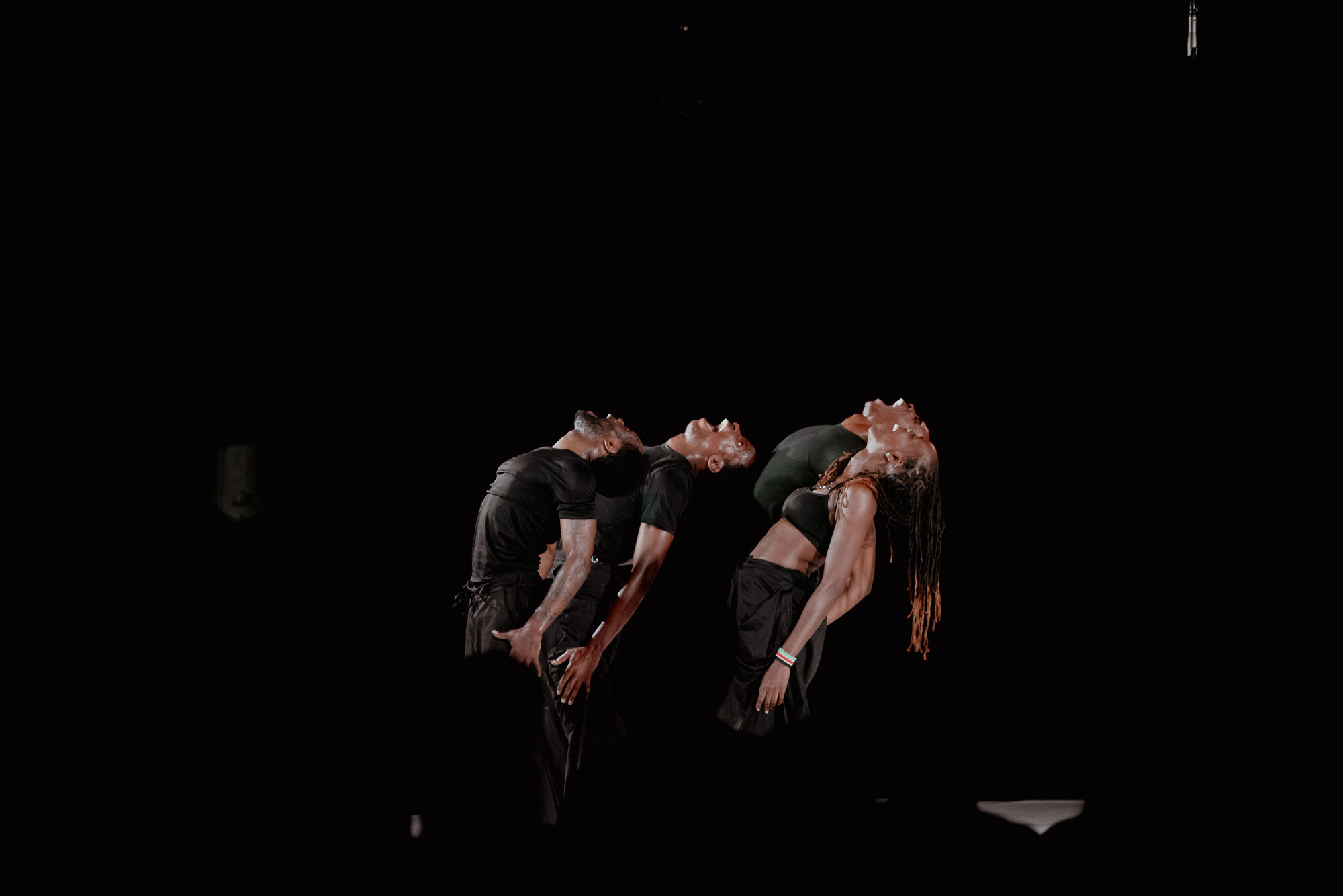 A group of dancers lean back onstage.
