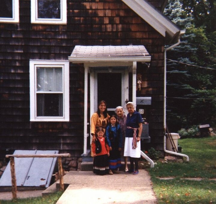 Five people stand in front of a house