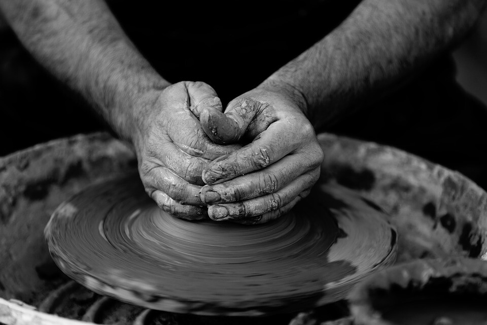 Hands shaping clay on a spinning pottery wheel.