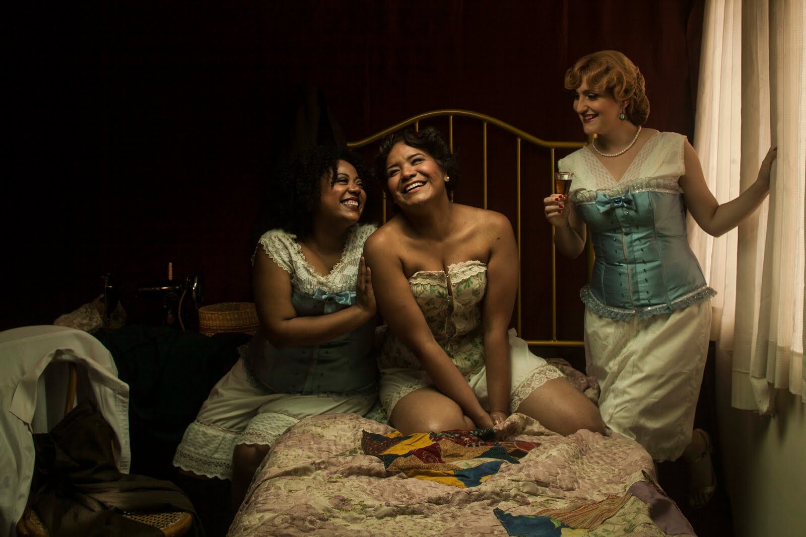 Three women sit on a bed.