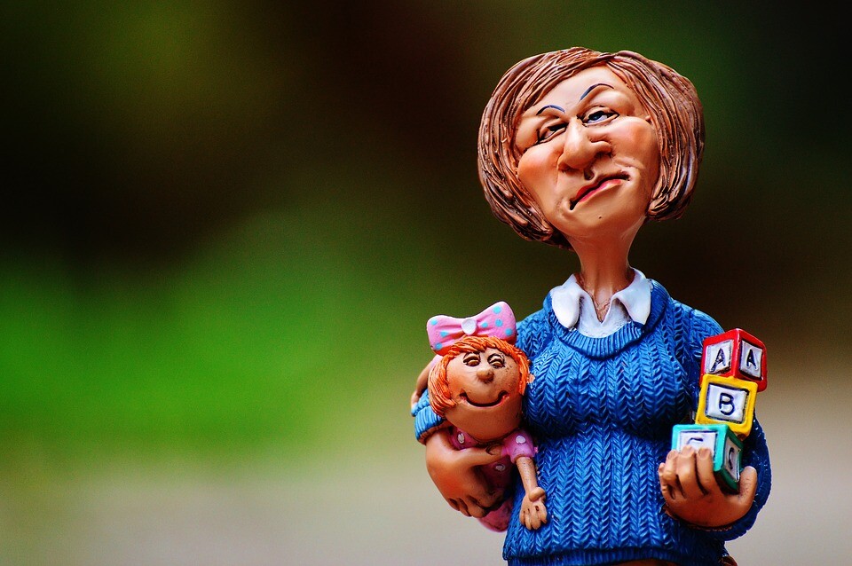A clay model of a woman holding a baby and some toys.