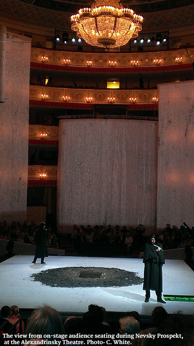 Two actors stand on either side of a dirt-lined hole in the stage with their backs facing each other.