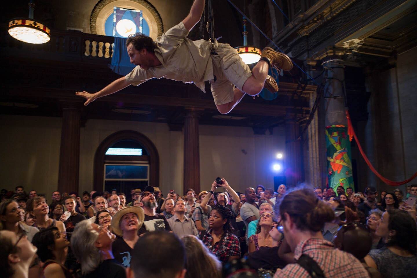 A man flies on wires above a crowd.