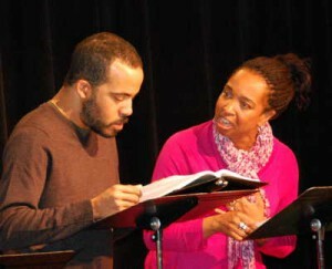 Two Black performers read a scene together on-stage.