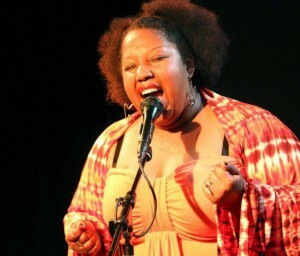 A Black performer sings into a microphone.